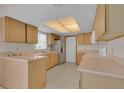 Bright kitchen featuring light wood cabinetry, tile flooring, and stainless steel refrigerator at 572 Floral Dr, Kissimmee, FL 34743