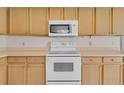 Close-up of a well-equipped kitchen with a white electric stove, microwave, and ample cabinet space at 572 Floral Dr, Kissimmee, FL 34743