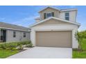 Two story home with a beige colored garage, a small lawn and manicured landscaping at 815 Lake Dell Rd, Dundee, FL 33838