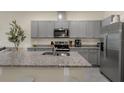 Well-equipped kitchen with gray cabinets, stainless steel appliances, and a granite-topped island at 1219 Lido Dr, Howey In The Hills, FL 34737