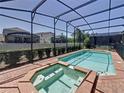Private screened-in pool and spa with brick surround and lush landscaping at 1614 Lima Ave, Kissimmee, FL 34747
