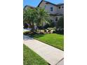 Beautiful landscaping with palm trees and plants adorns the front yard of this home at 2289 Seven Oaks Dr, St Cloud, FL 34772