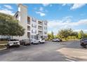 A three-story condo building with balconies, neutral siding, and ample parking shaded by mature trees at 3175 Feltrim Pl # 101, Kissimmee, FL 34747