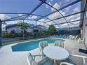 Inviting screened-in pool area with lounge chairs and outdoor dining setup on a sunny day at 4707 Pershoie Ln, Kissimmee, FL 34746