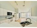 Bright kitchen featuring white cabinets, appliances, tile flooring, and views of adjacent breakfast nook at 664 Eagle Pointe S, Kissimmee, FL 34746