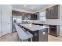 Modern kitchen boasts stainless steel appliances, dark cabinets, quartz countertops, and a central island with seating at 824 Ofanto Way, Haines City, FL 33844