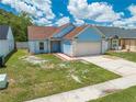 Charming one-story blue home with a two-car garage and manicured front yard at 8322 Cascade Oaks Dr, Orlando, FL 32822