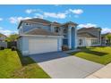 Beautifully landscaped blue home featuring an attached garage and welcoming front yard at 12303 Bohannon Blvd, Orlando, FL 32824