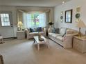 Bright living room featuring neutral carpeting, a large window with stylish curtains, and classic furniture at 1410 Sanchez Ct, Lady Lake, FL 32159