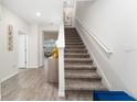 Bright entryway featuring a staircase with carpeted steps and white risers, complemented by wood-look flooring at 14416 Orchid Island Dr, Orlando, FL 32827