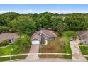 An aerial view of a single-story home with a brick driveway, lush landscaping, and private backyard at 14610 Wishing Wind Way, Clermont, FL 34711