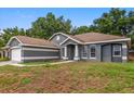 Inviting single-story home featuring a well-manicured lawn, brick driveway, and an attached two-car garage at 14610 Wishing Wind Way, Clermont, FL 34711