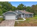 Charming single-story home featuring a brick driveway, well-maintained lawn, and inviting curb appeal at 14610 Wishing Wind Way, Clermont, FL 34711