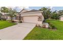 Home's two-car garage with a driveway, stone accents, and verdant lawn at 1746 Golfview Dr, Kissimmee, FL 34746