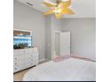 Bright bedroom with stylish ceiling fan, a dresser with television, and a light pink blanket accent at 2567 Oneida Loop, Kissimmee, FL 34747