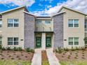 Close-up of a modern townhome's front facade with stacked stone detail and vibrant green doors at 2970 Protagonist St, Kissimmee, FL 34746