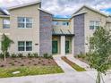 Modern townhome featuring stacked stone accents, lush landscaping, and two vibrant green front doors at 2970 Protagonist St, Kissimmee, FL 34746