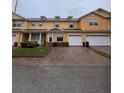 Inviting yellow townhome with a brick paved driveway leading to a single-car garage for convenient parking at 4981 Alita Ter, St Cloud, FL 34769