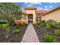 Charming home featuring a brick walkway leading to the front door and lush landscaping at 517 Milano Rd, Poinciana, FL 34759