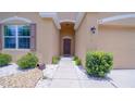 Inviting front entrance with a pathway flanked by decorative stone and lush greenery, enhancing curb appeal at 647 Washington Way, Haines City, FL 33844