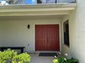 Warm home entrance with a beautiful red double-door and decorative foliage around the home at 7200 Green Pine Ct, Orlando, FL 32819