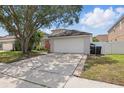 View of the home’s driveway, two-car garage, landscaping, and exterior at 14006 Yellow Wood Cir, Orlando, FL 32828