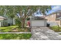 Front exterior featuring a two-car garage, manicured lawn and landscaping at 14006 Yellow Wood Cir, Orlando, FL 32828