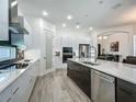 Modern kitchen with stainless steel appliances, a large island, sleek countertops, and wood-look tile flooring at 235 Hampton Loop, Davenport, FL 33837