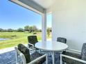 Covered patio with a table and chairs offers a view of a lush green landscape at 235 Hampton Loop, Davenport, FL 33837