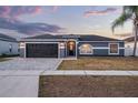 Charming single-story home featuring a dark gray garage door, neutral paint, and a well-manicured lawn at 2520 Jasmine Trace Dr, Kissimmee, FL 34758