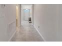 Bright hallway with tile flooring leading to the home's entrance showcasing neutral color scheme at 3844 Cabo Rojo Dr, St Cloud, FL 34772