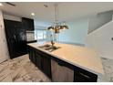 Open kitchen featuring a large island with modern light fixtures and black cabinets at 4804 Marcos Cir, Kissimmee, FL 34758