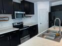 Modern kitchen featuring sleek black cabinetry and stainless steel appliances at 4804 Marcos Cir, Kissimmee, FL 34758