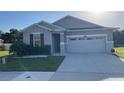 Inviting single-Gathering home featuring stone veneer accents, a two car garage, and green lawn at 5306 Meadow Song Dr, Okahumpka, FL 34762