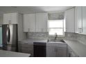 Bright kitchen featuring stainless steel refrigerator, white cabinets, and marble backsplash at 894 Superior St, Deltona, FL 32725