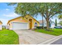 Inviting home showcasing a two-car garage and lush lawn with a mature tree, perfect for suburban living at 1113 Casterton Cir, Davenport, FL 33897