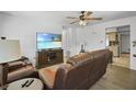 Cozy living room features a leather sofa, ceiling fan, and a large flat-screen television at 1408 Polk City Rd, Haines City, FL 33844
