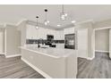 Bright kitchen featuring quartz countertops, white cabinetry, stainless steel appliances and modern pendant lighting at 242 Anson Dr, Kissimmee, FL 34758