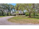 Charming two-story home with covered porch and carport surrounded by lush greenery and mature trees at 2652 N Woodland Blvd, Deland, FL 32720