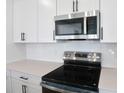 Modern kitchen featuring stainless steel appliances, white cabinets, and tile backsplash at 3629 Sublett Loop, Tavares, FL 32778