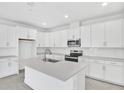 Modern, all-white kitchen featuring an island, stainless steel appliances, and ample cabinet space at 4071 Bannock Ave, Tavares, FL 32778