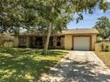 Single-story home with attached garage, featuring well-maintained front yard and mature trees at 42 Chip Ct, Kissimmee, FL 34759