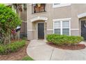 Close-up of a welcoming townhouse entrance with lush green landscaping and a 'hello' doormat at 6548 Swissco Dr # 61, Orlando, FL 32822