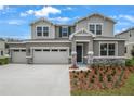 Beautiful two-story gray home featuring a spacious three-car garage and attractive landscaping at 1027 Cloud Ridge Ct, Mount Dora, FL 32757