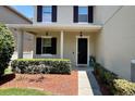Inviting front porch with manicured hedges, dark shutters, and a welcoming entrance with a black front door at 1043 Tourmaline Dr, Kissimmee, FL 34746