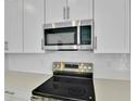 Close-up of a kitchen featuring stainless steel appliances, white subway tile backsplash and sleek white cabinets at 1051 Cloud Ridge Ct, Mount Dora, FL 32757