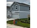 Side view of a gray two-story home with a two-car garage and neatly trimmed landscaping at 1053 Waterfall Blvd, Davenport, FL 33837