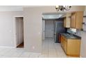 Kitchen showcasing tile floors, neutral countertops, stainless refrigerator, and seamless flow to adjacent living space at 114 N Alderwood St, Winter Springs, FL 32708