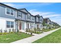 Row of townhomes showcasing light blue exteriors, landscaped lawns, and front sidewalks at 12190 Plumpton Dr, Winter Garden, FL 34787