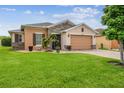 Inviting home exterior with a lush green lawn, paver driveway, and stone details at 1272 Bonita Canyon Dr, Poinciana, FL 34759
